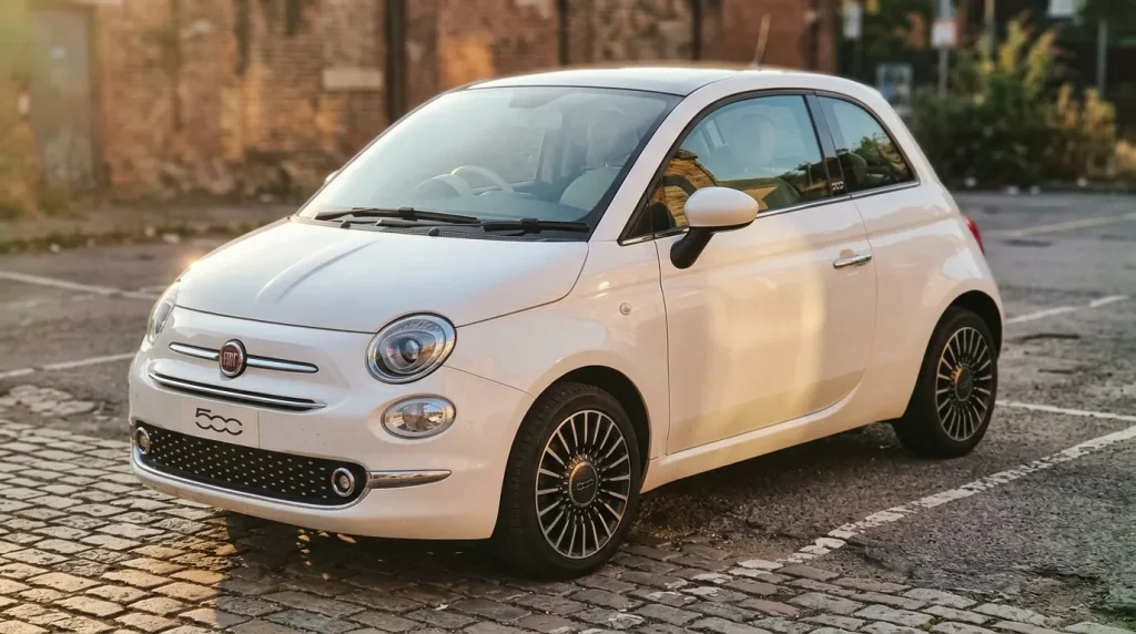Fiat 500 blanche garée sur rue pavée urbaine